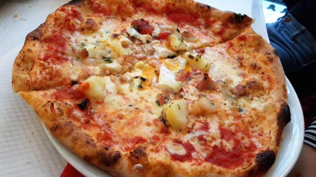 Pizza Paesana : sauce tomate, fromage, lardons, pommes de terre, œuf et oignons 